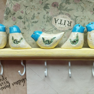 Wieszak z ptaszkami o niebieskich główkach na słonecznym drewienku