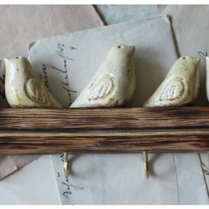 Wieszak z piaskowymi ptaszkami na opalonym drewnie