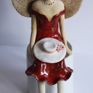 Anioł z kapeluszem na kolanach