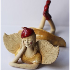 Anioł leżący w piaskowej sukience w beretce