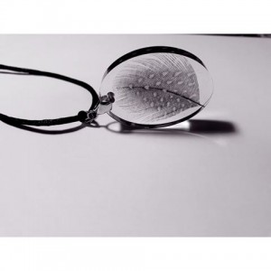 Owalna zawieszka z czarno-białym piórkiem