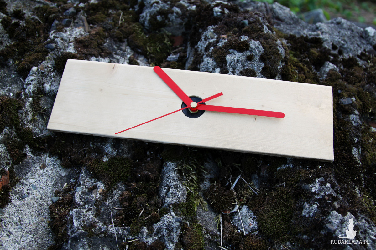 Zegar na drewnianej deseczce z czerwonymi wskazówkami