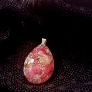 Naszyjnik w kształcie łezki. Zostały w nim zatopione suszone kwiaty takie jak gipsówka