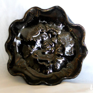 Okrągły falowany czarny talerzyk z kwiatem