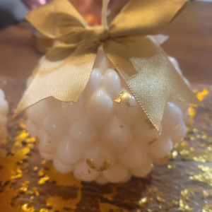 Urocza świeca sojowa z kokardą I płatkami złotej folii.